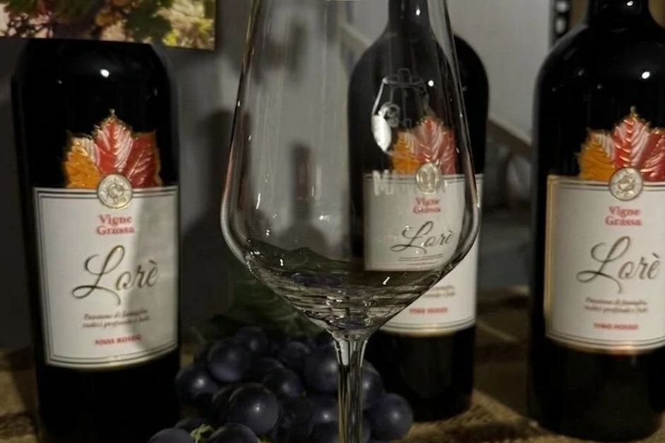 Bottiglie e calice di vino rosso Lorè in degustazione